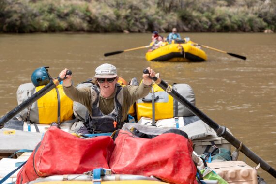 An OARS guide rows on the Colorado River in Grand Canyon