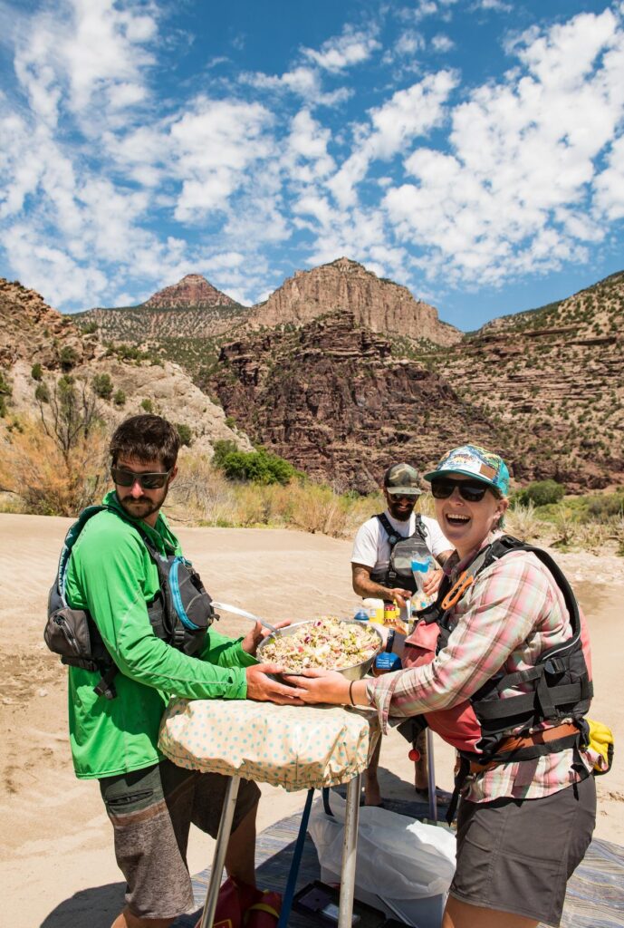 Several people prepare a picnic lunch in a scenic river canyon.
