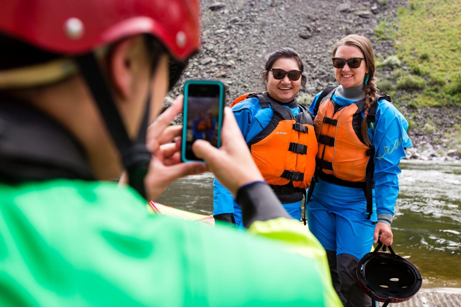 A guide uses a phone to take a picture of two guests on an OARS trip.