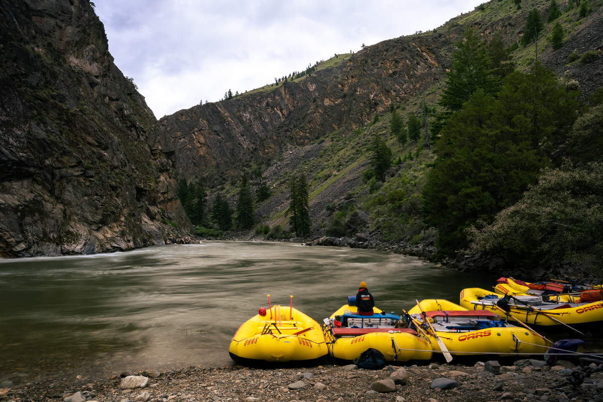 Several yellow boats tied up on the shore of Idaho's Middle Fork Salmon River with dramatic canyon walls in the background