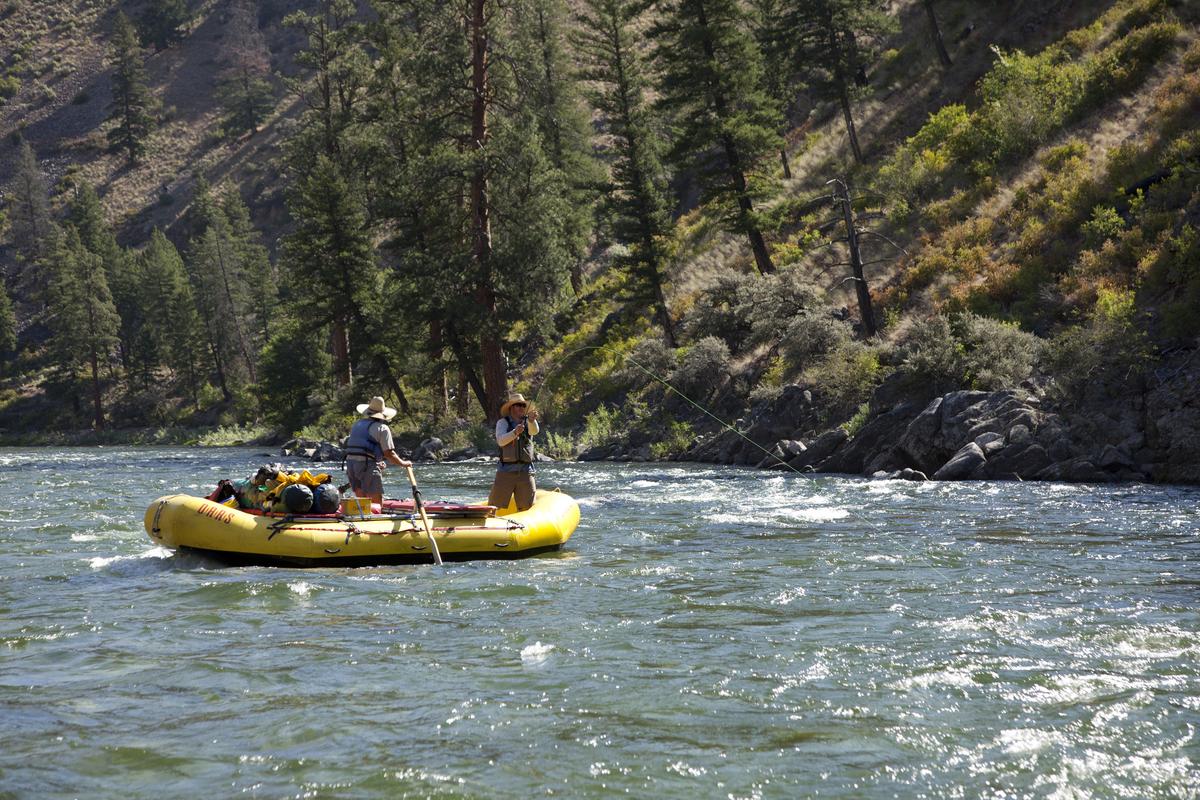 A man fishes off of a boat floating downstream on the Salmon River