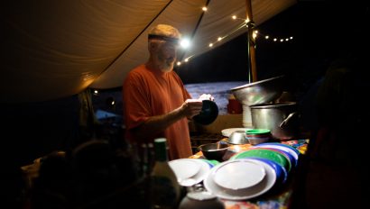 An OARS guide does dishes in the dark on a Grand Canyon rafting trip