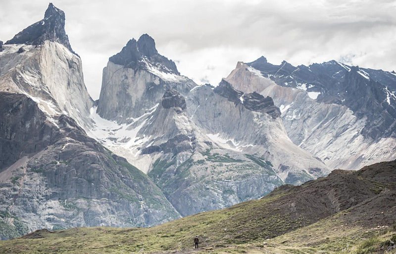 Scenic shot of rising mountains as a hiker walks in the distance in Patagonia.