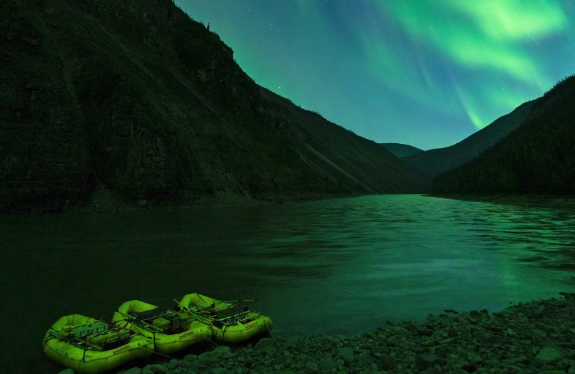 Yellow rafts at shore under the glowing green Northern Lights.
