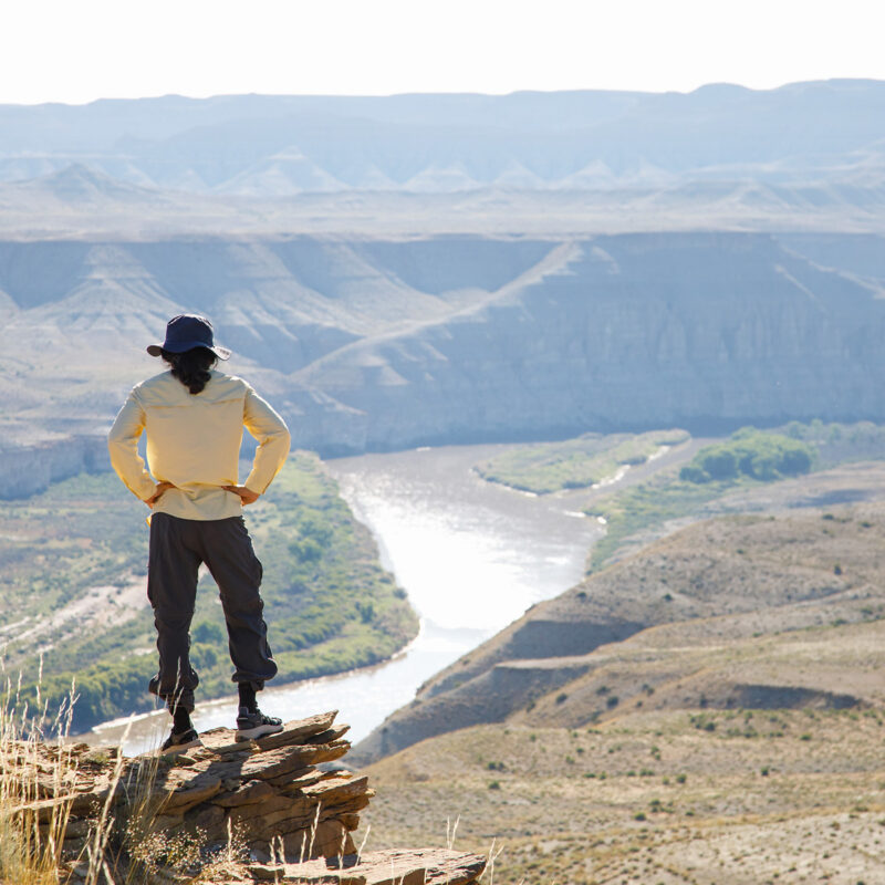 A hiker stands high above the Green River and takes in the view of Desolation Canyon in Utah.