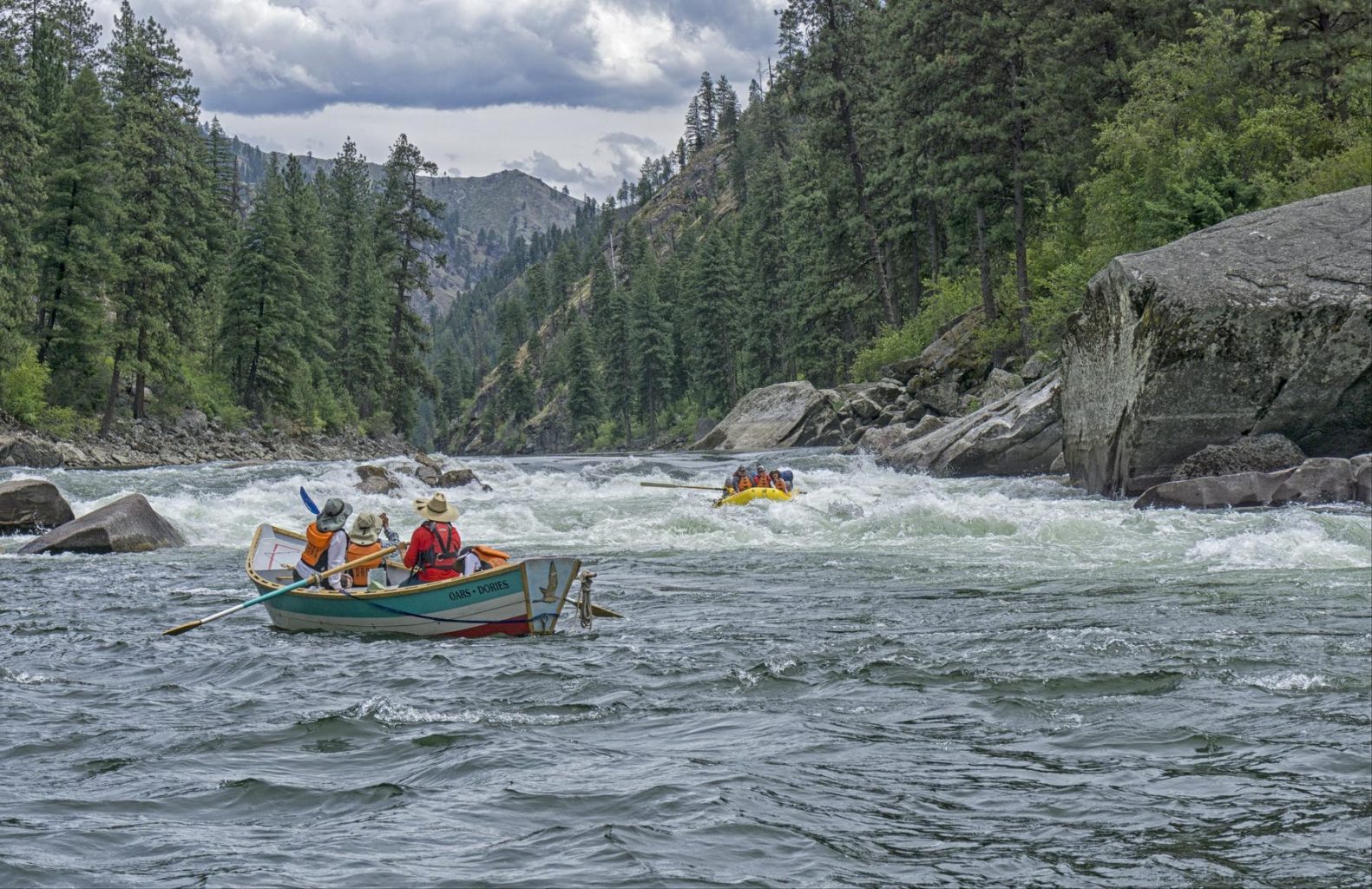 A yellow OARS rafting going down Black Creek Rapid on the Main Salmon River while a dory watches. 