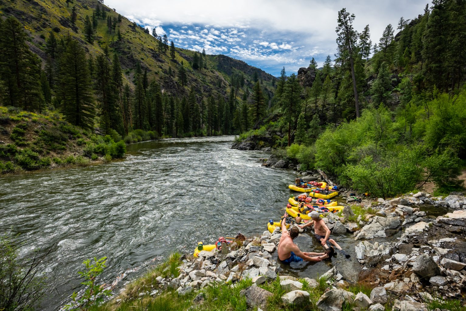 Two guys soak in a hot spring on the edge of the Middle Fork Salmon River in Idaho