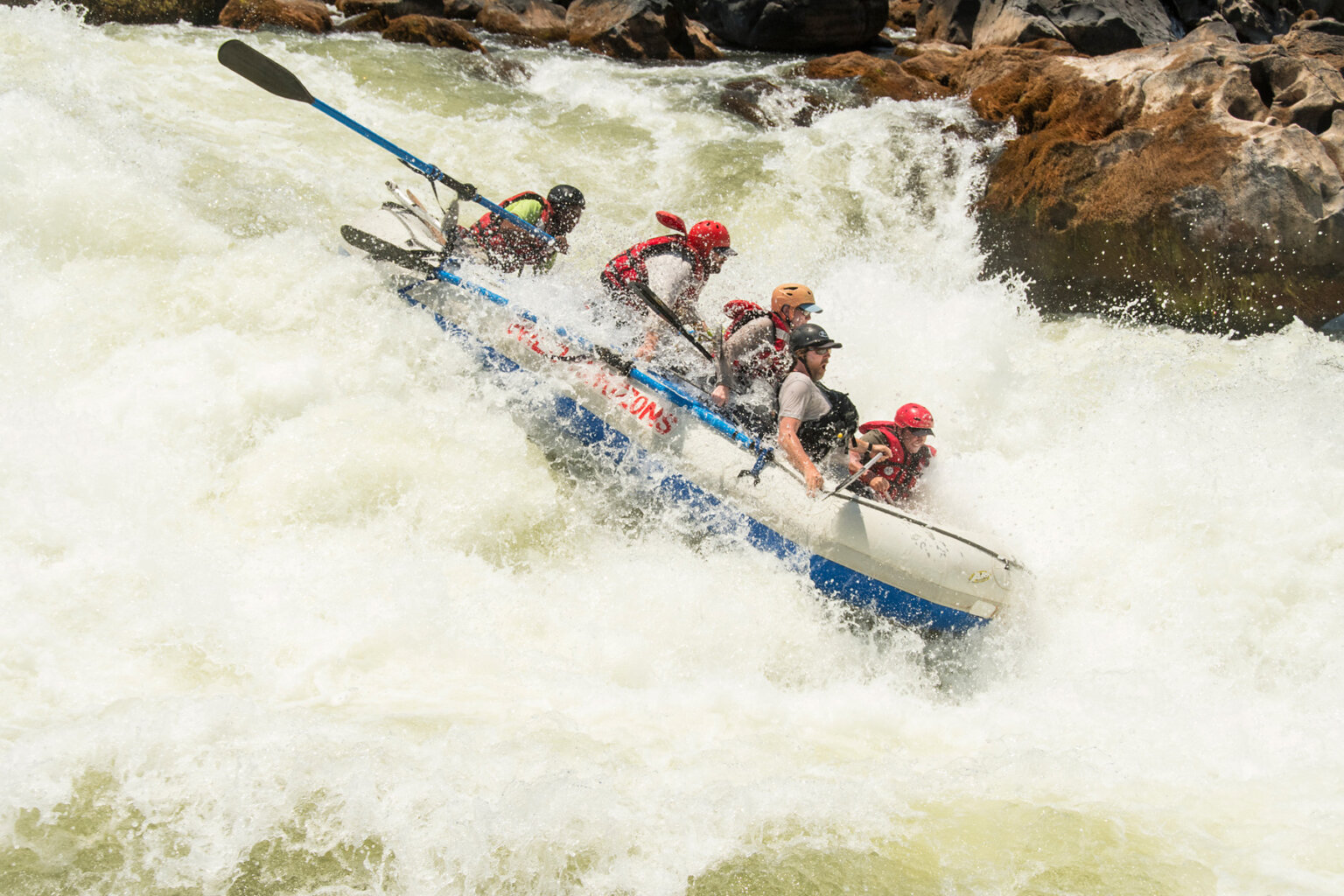 Paddlers hold on tight as their raft, steered by a guide on oars, veers downward in a massive rapid on the Zambezi River.