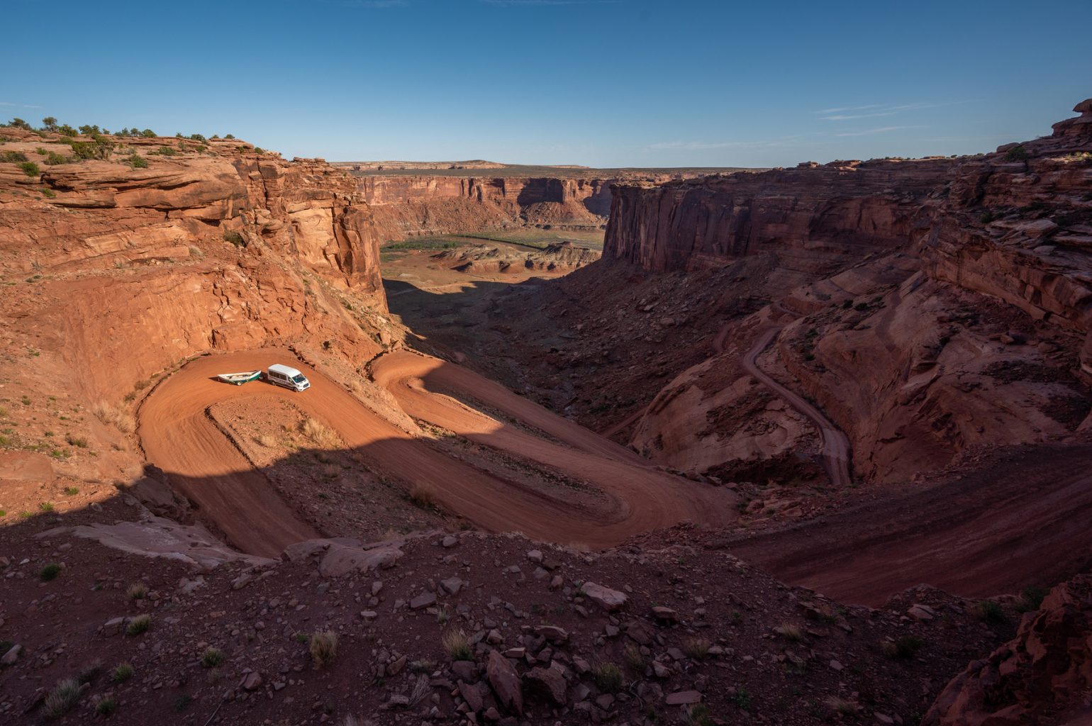 An OARS van pulling a dory goes down a winding road in Utah