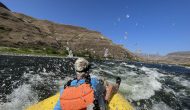 A guest on an OARS rafting trip rides through a rapid on the Snake River