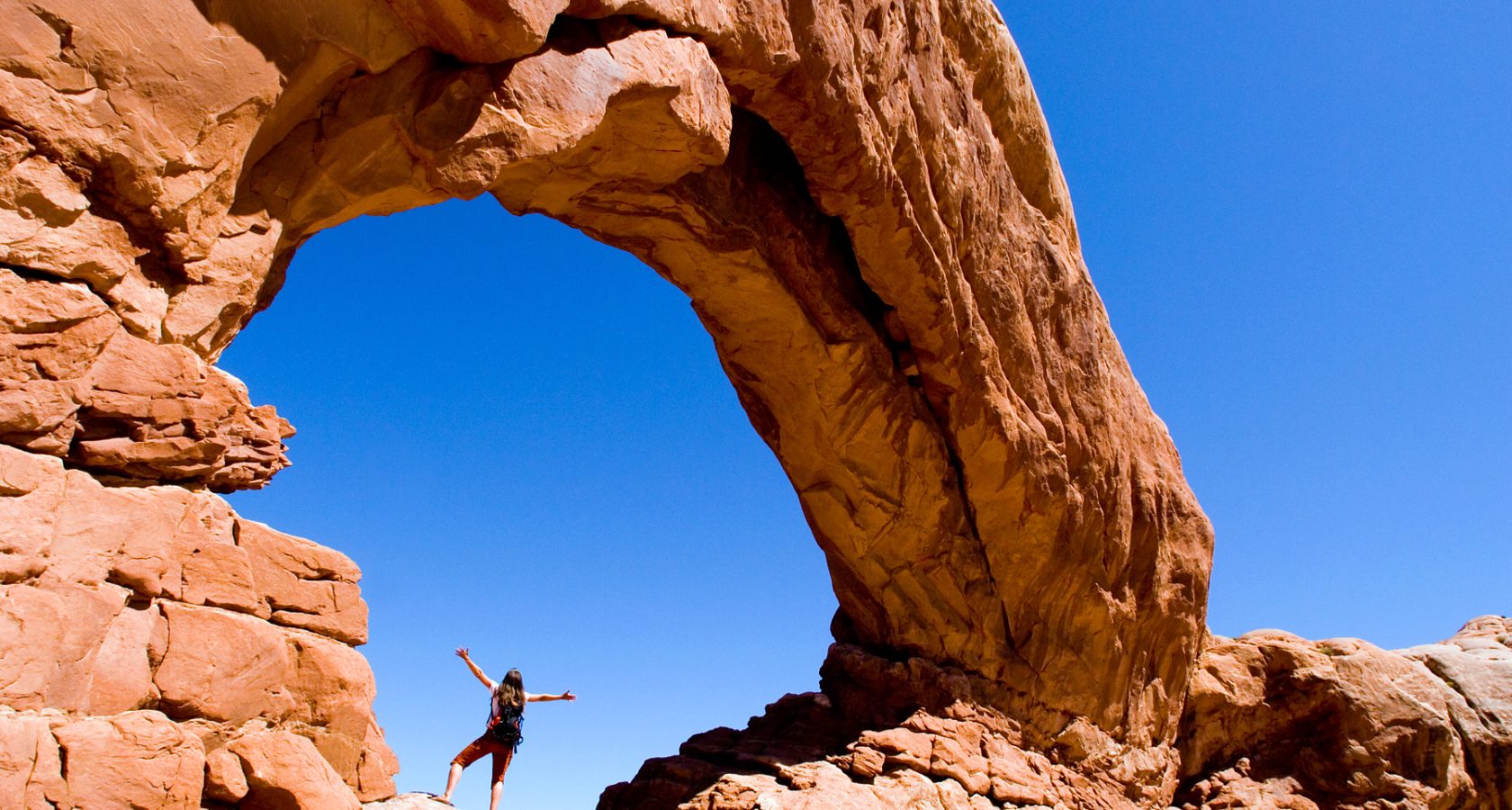 Woman standing under an arch in Arches National Park