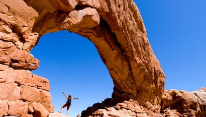 Woman standing under an arch in Arches National Park