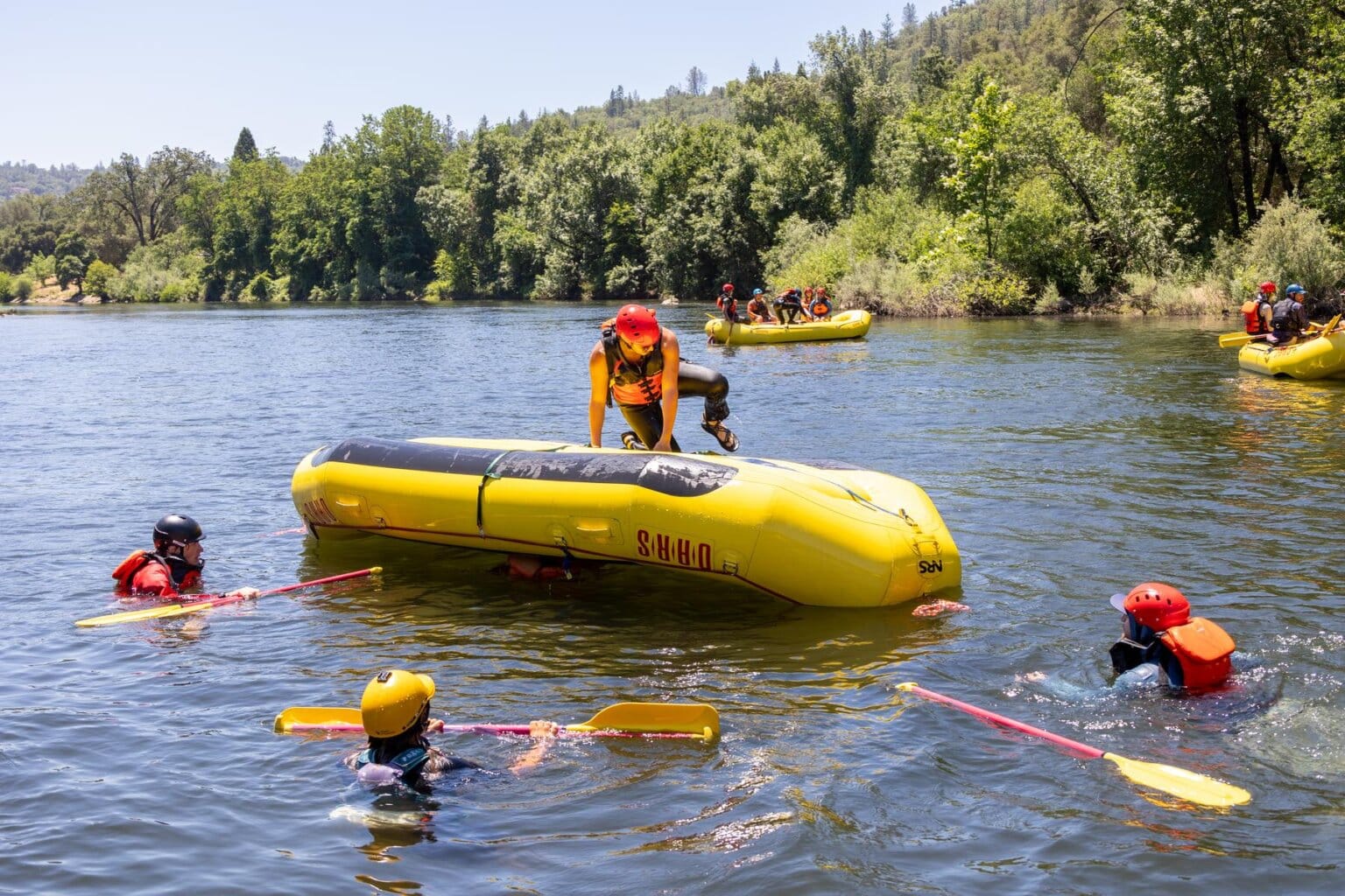 A student in OARS guide school climbs on top of a raft on the South Fork of the American River