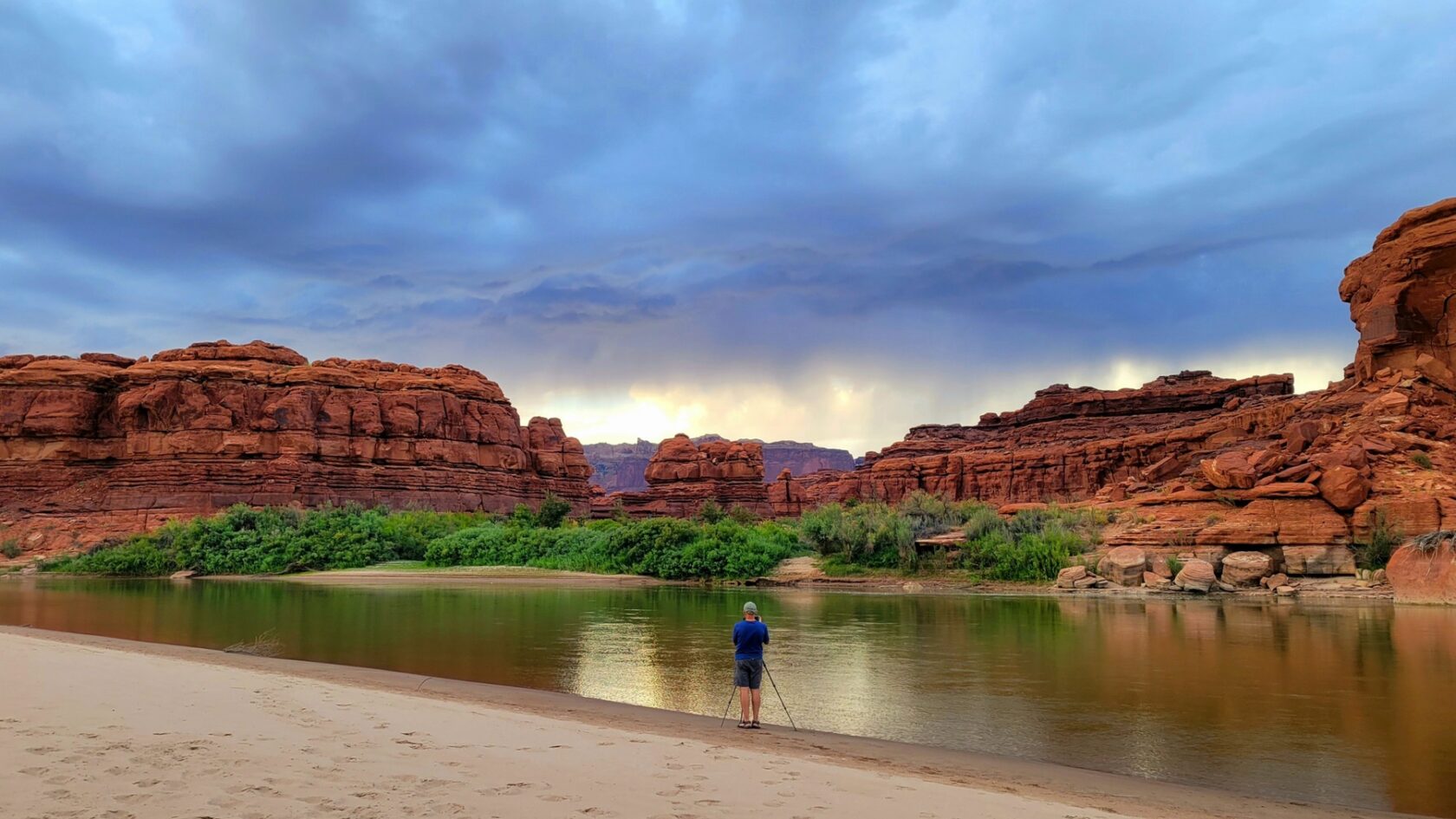 A person captures a stormy sunset unfolding along the Colorado River in Canyonlands National Park