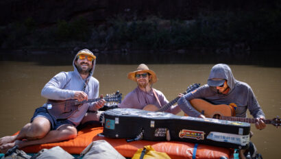 Three river guides play instruments on yellow rafts