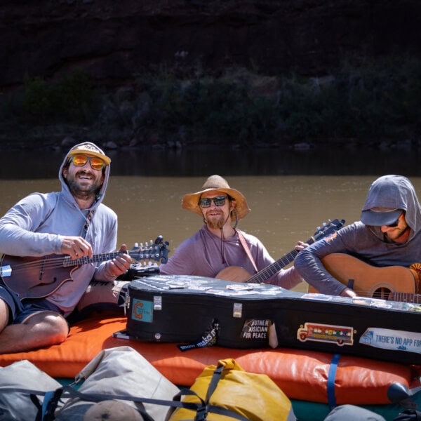 Three river guides play instruments on yellow rafts