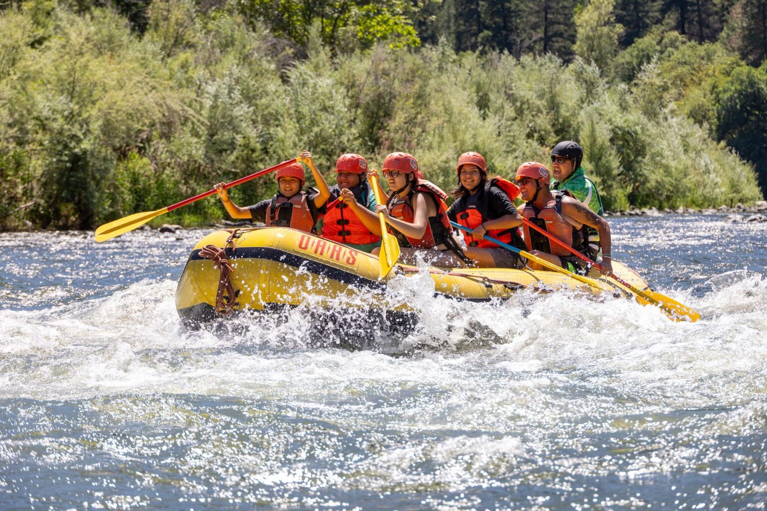 A group of youth splashes through a rapid while rafting on the Rogue River.