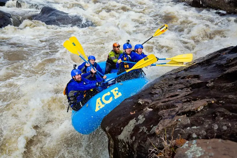 A blue raft bouncing off of a rock wall in Pillow Rapid on West Virginia's Gauley River