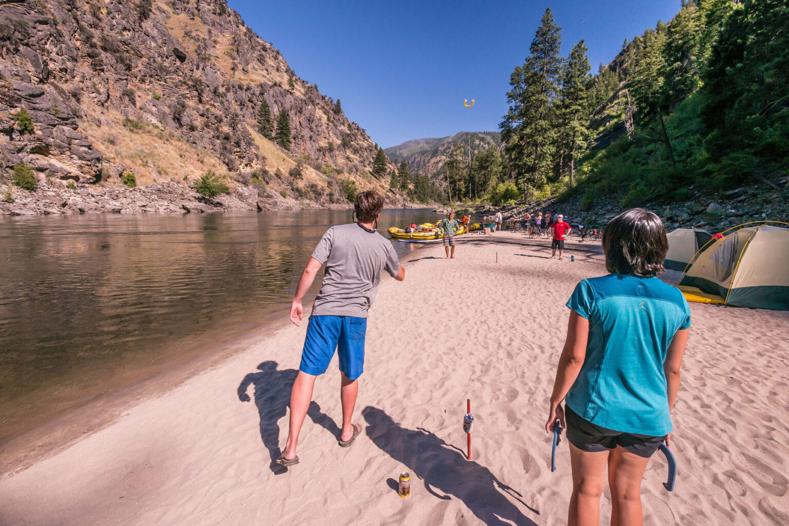 Four people playing horseshoes on a sandy beach along the Main Salmon River in Idaho.