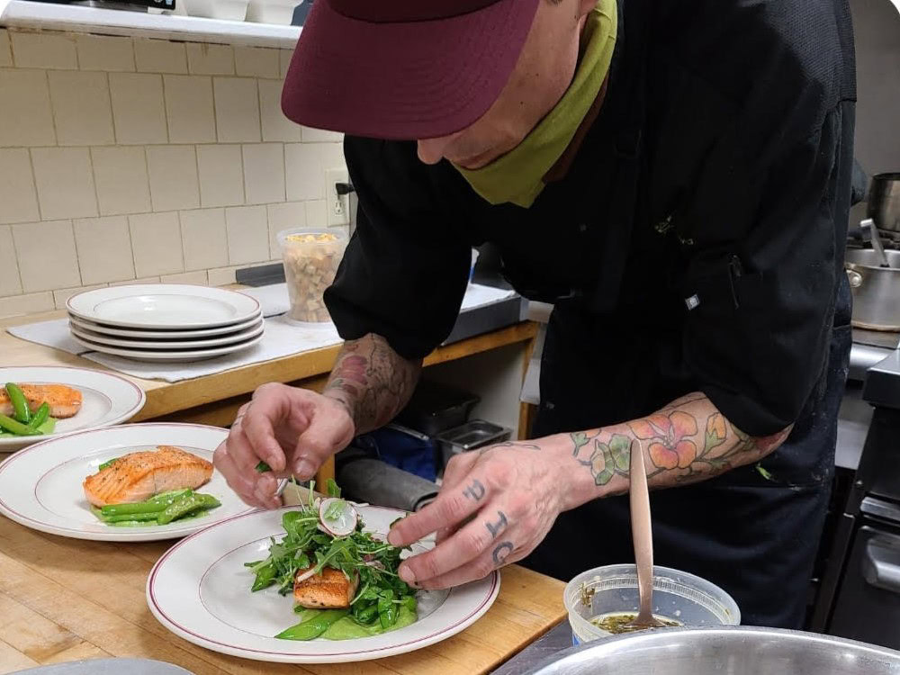 Chef Keenan McGrew prepares plates for service in a restaraunt kitchen.