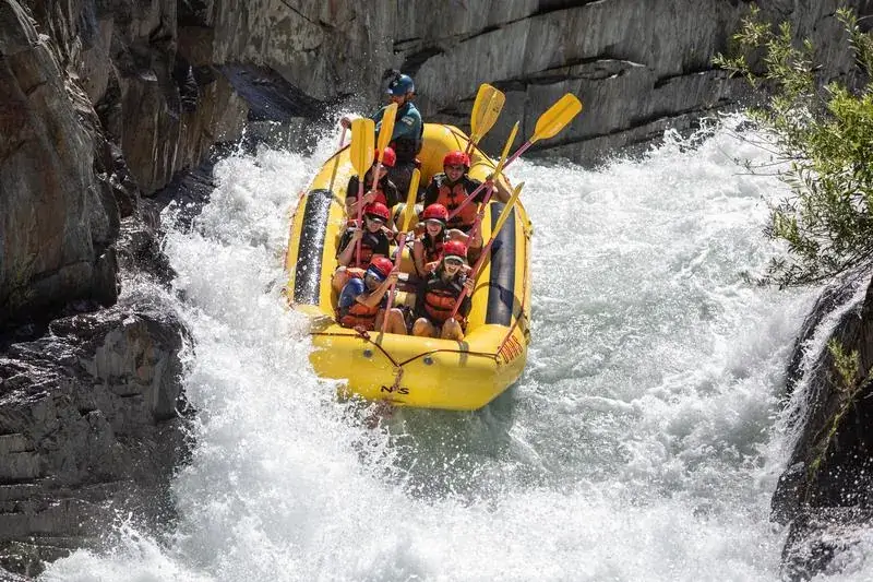 A yellow raft carrying several people navigates a narrow channel on the Middle Fork of the American River known as Tunnel Chute Rapid.