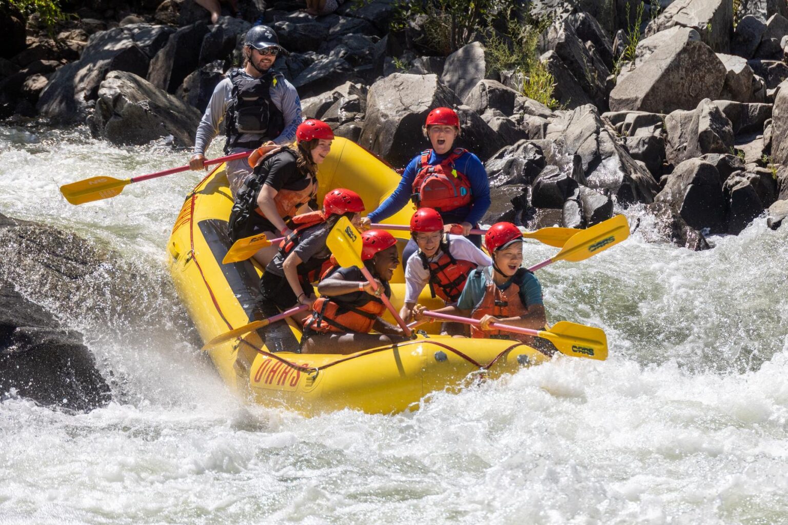 A group of students having a blast as they go through a rapid on the South Fork American in a yellow raft.
