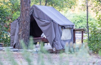 A canvas tent on the American River with the doors open to show the beds inside.