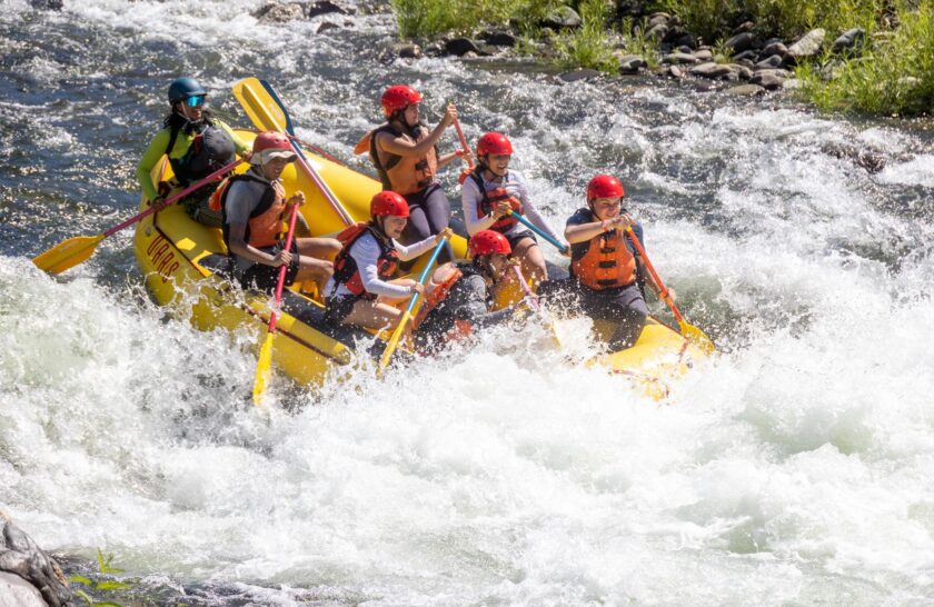 A yellow raft full of paddlers goes through a rapid on the South Fork American River.