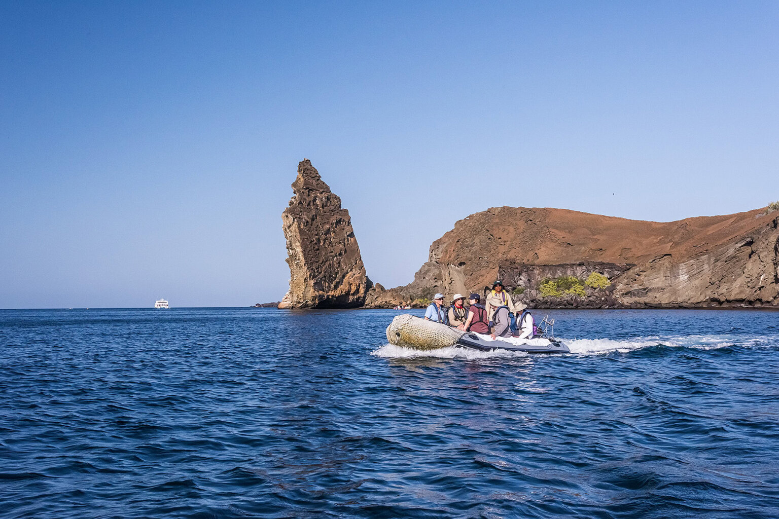 Guide and guests in a pango in front of rock pinnacle Bartolome Island Galapagos