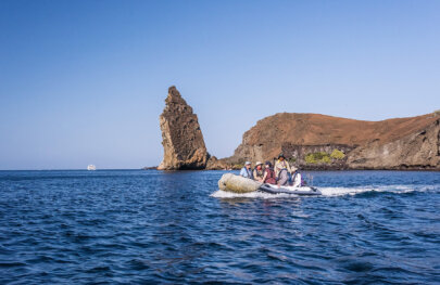 Guide and guests in a pango in front of rock pinnacle Bartolome Island Galapagos
