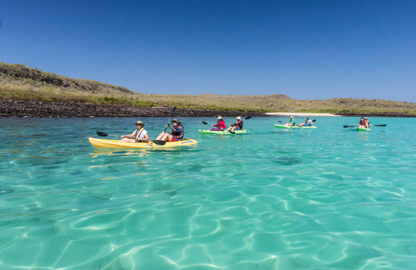 Guests paddle open, 2-seater kayaks over turquoise water of Galapagos
