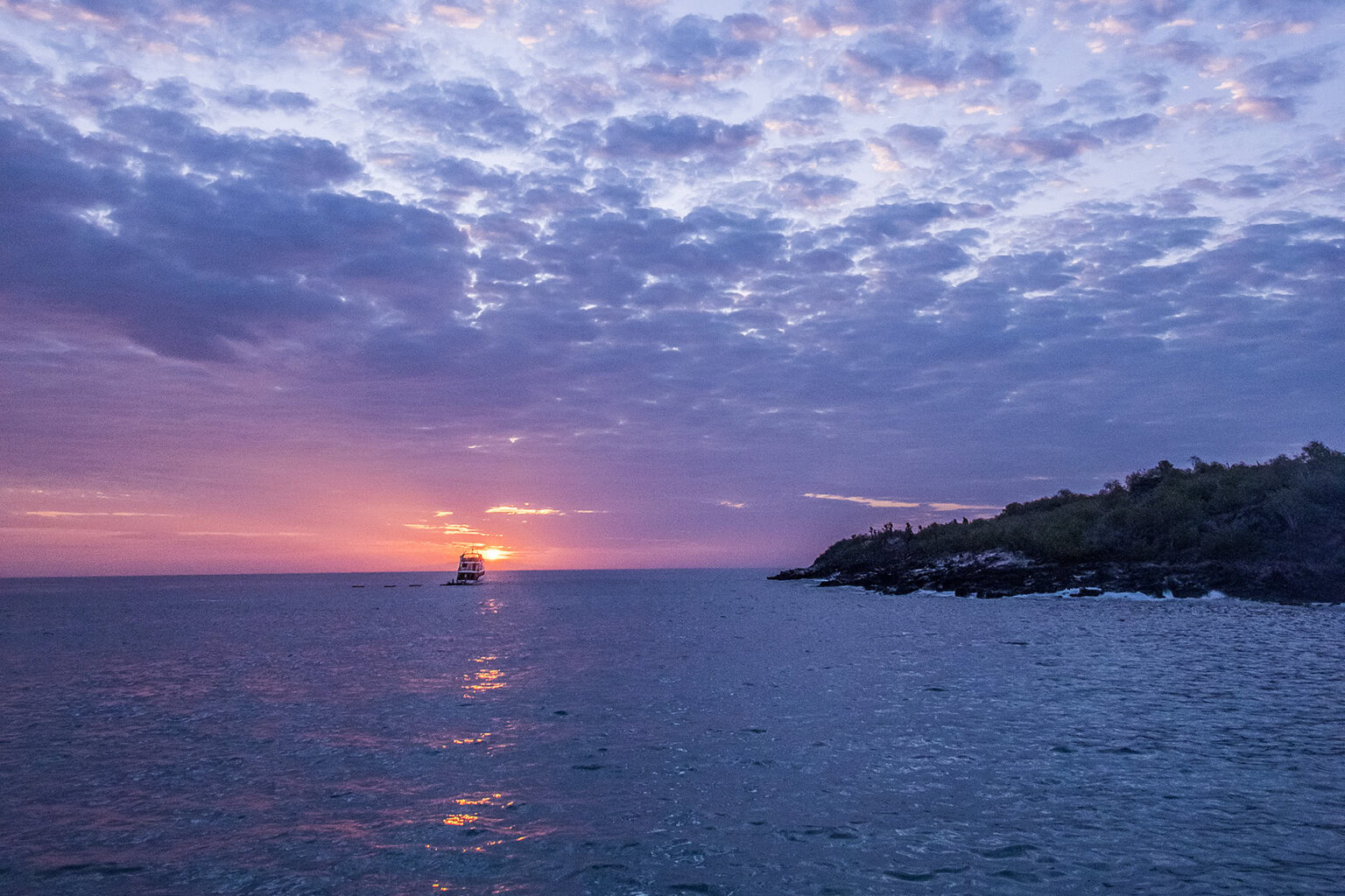 Boat sails into sunset on Galapagos Islands cruise
