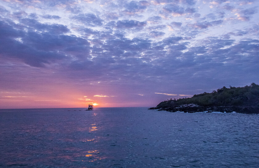 Boat sails into sunset on Galapagos Islands cruise
