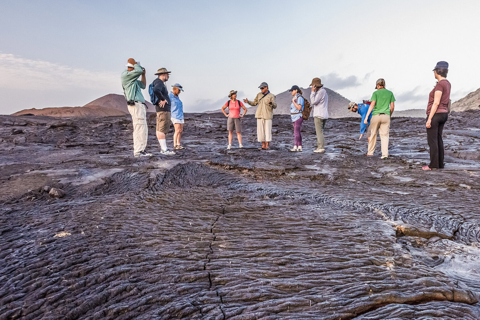 Guide explains "this was lava" as group stands on acres of bumpy dried lava, Galapagos Islands