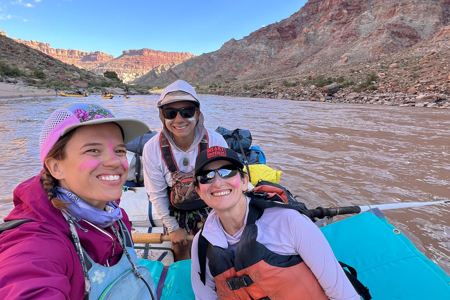 Three women on a raft with colorful sunscreen on their cheeks