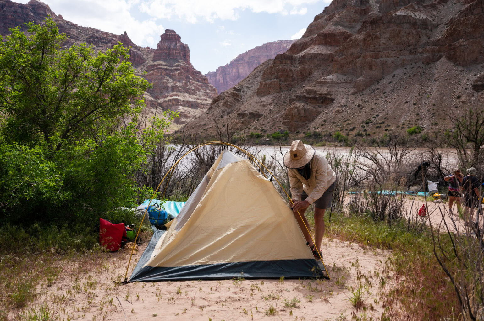 A camper sets up their tent in a flat, well-established campsite in Canyonlands National Park