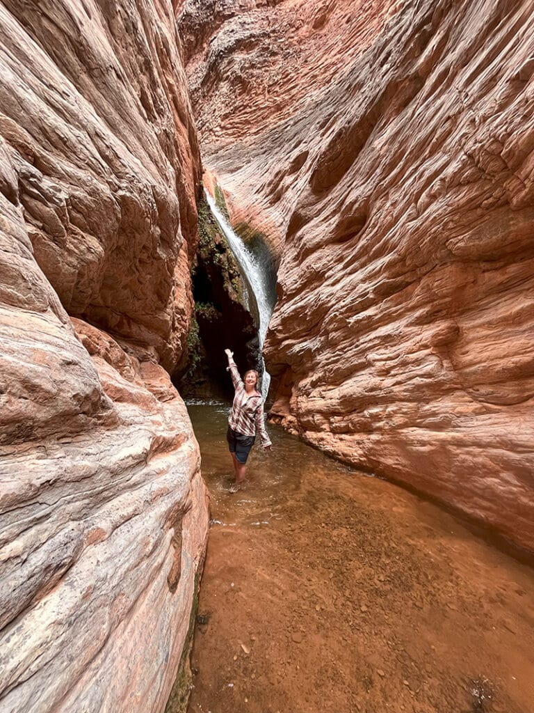 A waterfall spills down in a hidden erd rock alcove along Stone Creek in Grand Canyon