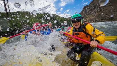 Two people encapsulated by a whitewater waver on a rafting trip