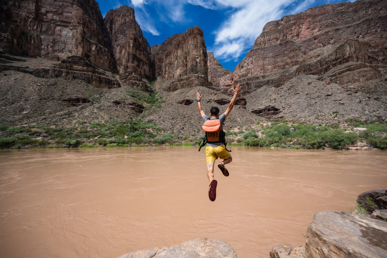 A man jumps off a rock into the Colorado River in Grand Canyon