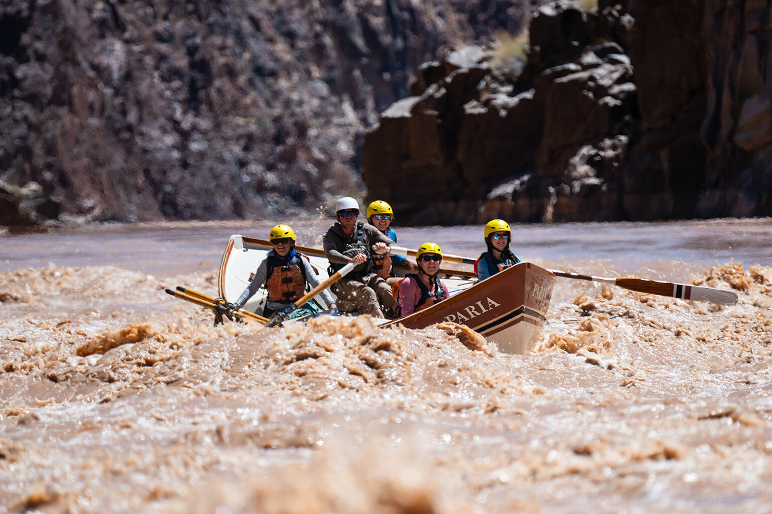 A guide rows a dory full of guests through whitewater on the Colorado River in Grand Canyon