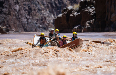 A guide rows a dory full of guests through whitewater on the Colorado River in Grand Canyon