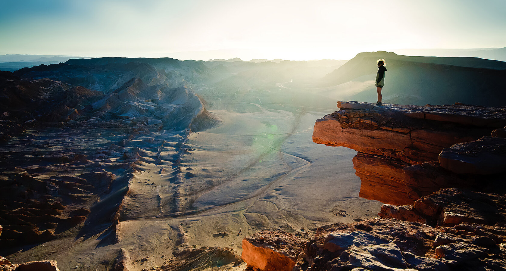 A person standing on a cliff overlooking Chile's vast Atacama Desert
