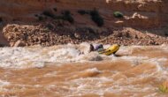 A guide rows an oar raft through Gypsum Rapid in Cataract Canyon on the Colorado River