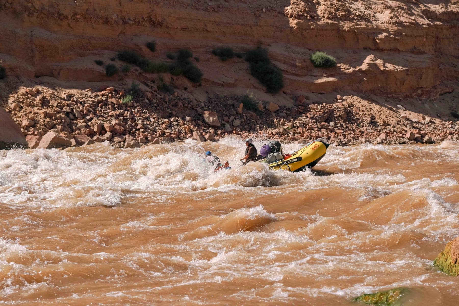 A guide rows an oar raft through Gypsum Rapid in Cataract Canyon on the Colorado River