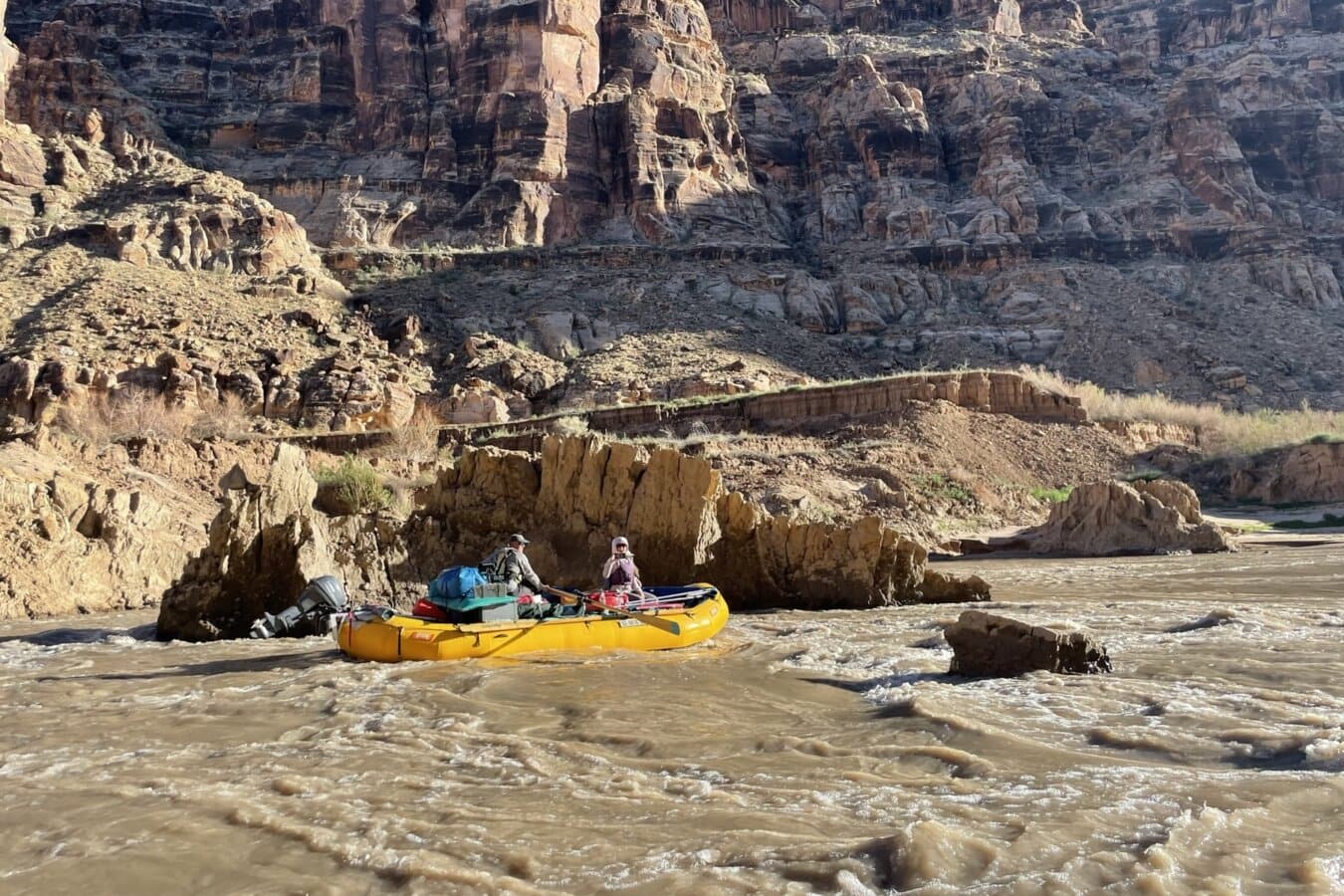 A raft rows through Space Slump mud rapid in the Returning Rapids corridor of Cataract Canyon on the Colorado River