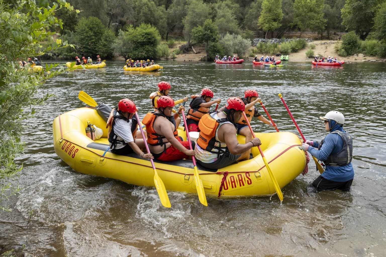 A group of OARS rafting guests practices paddling on the South Fork of the American River