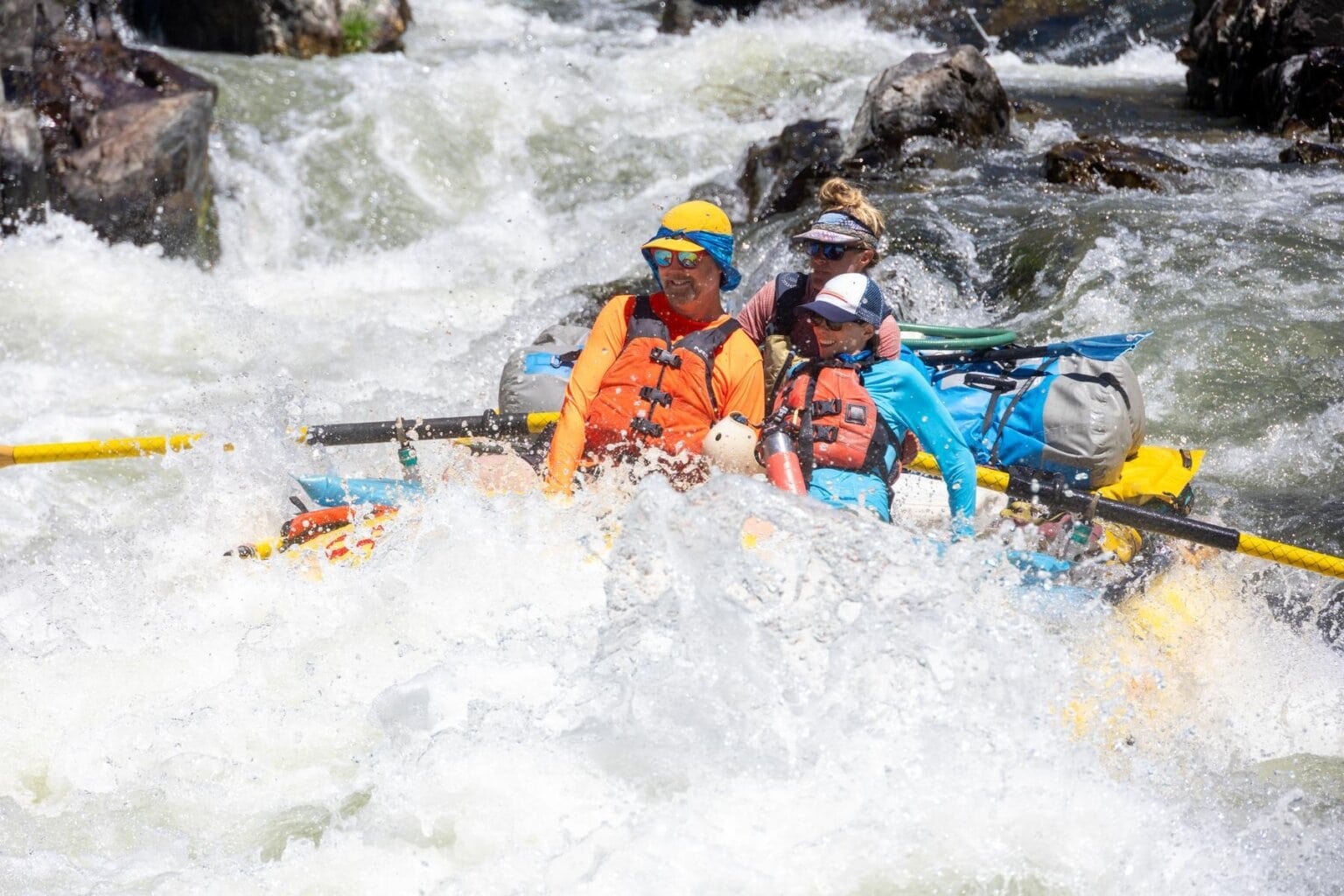 A couple sitting in the front of a yellow raft gets doused by whitewater on Oregon's Rogue River