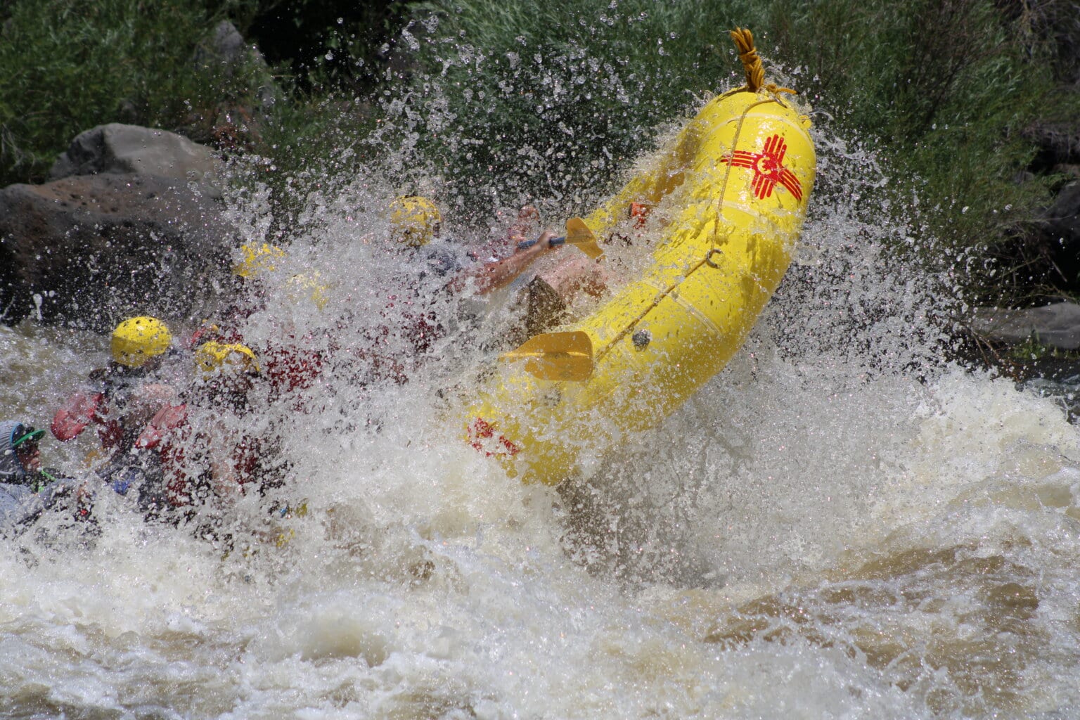 A yellow raft makes a huge splash going through a rapid on the Rio Grande River in New Mexico. 
