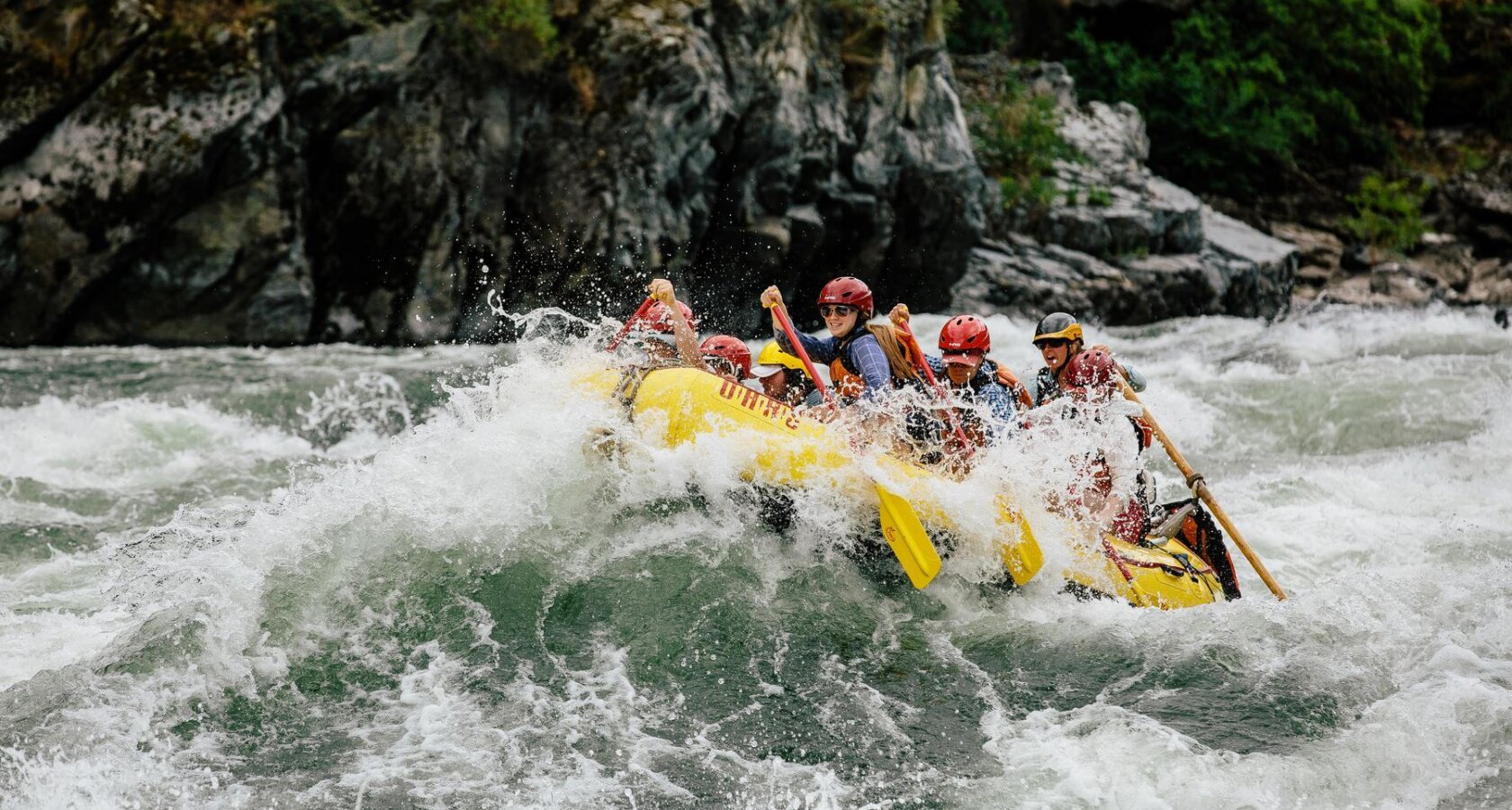 A yellow paddle raft splashes through a big wave on the Snake River in Hells Canyon