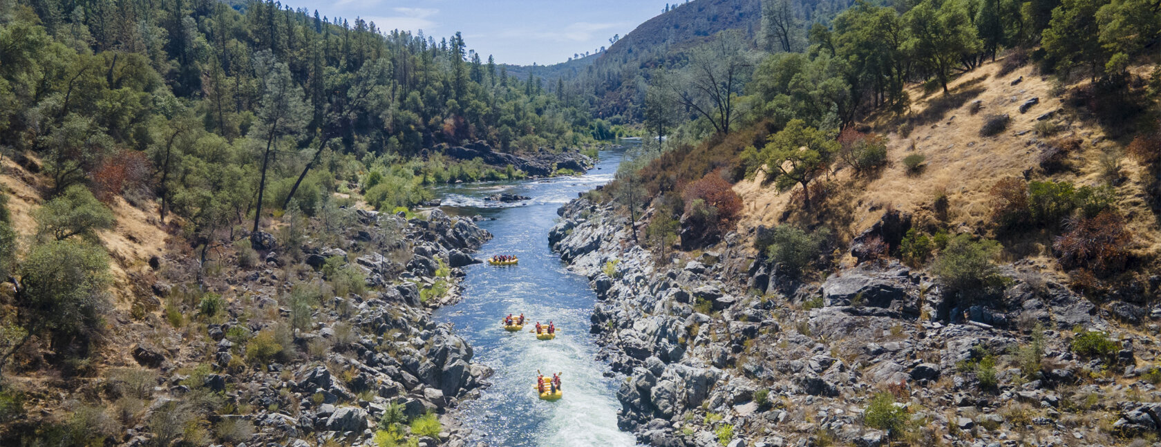 Aerial view of yellow OARS rafts floating down the South Fork American River
